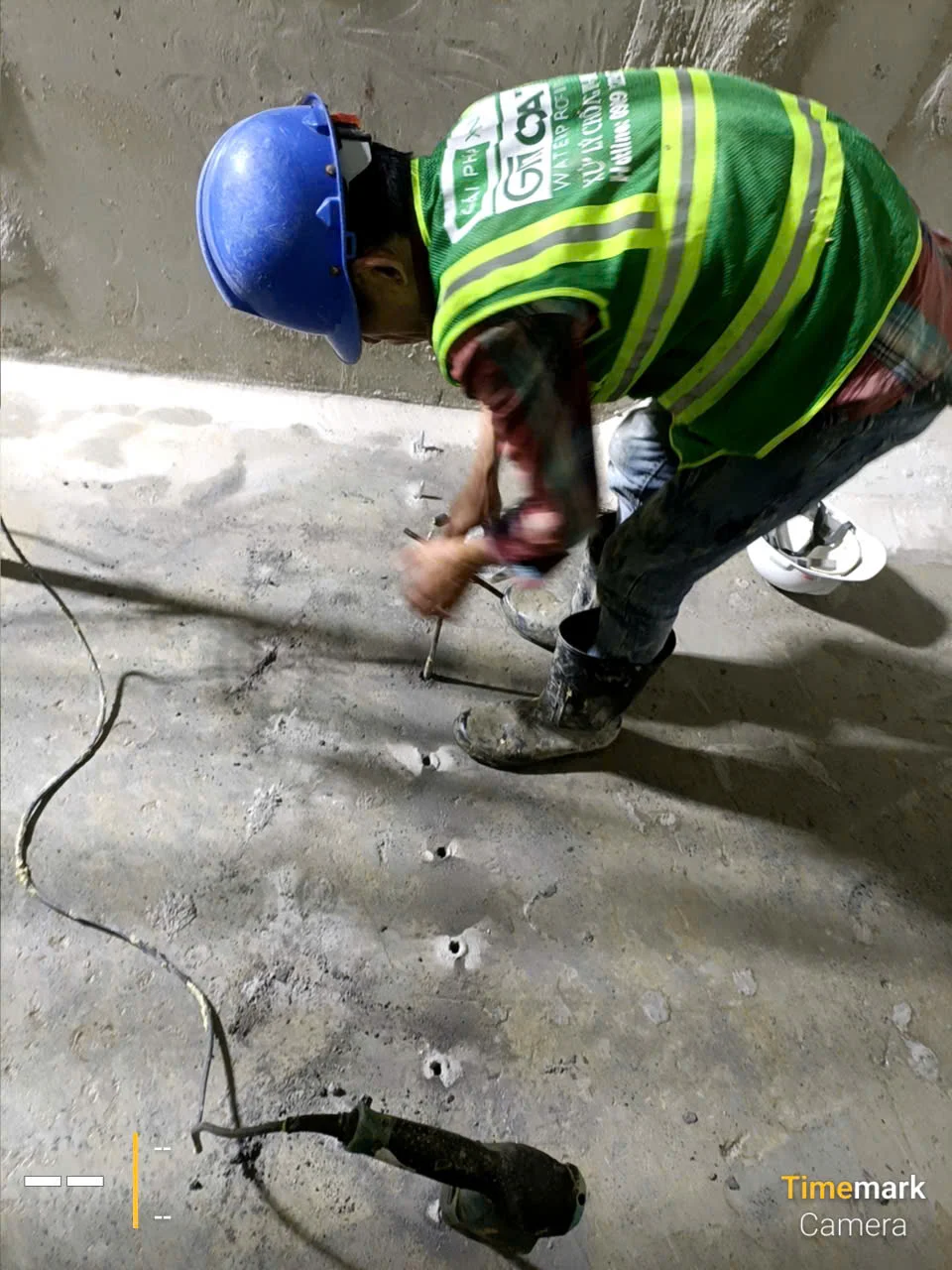 Thợ khoan lỗ xử lý chống thấm sàn hầm, mặc đồ bảo hộ lao động