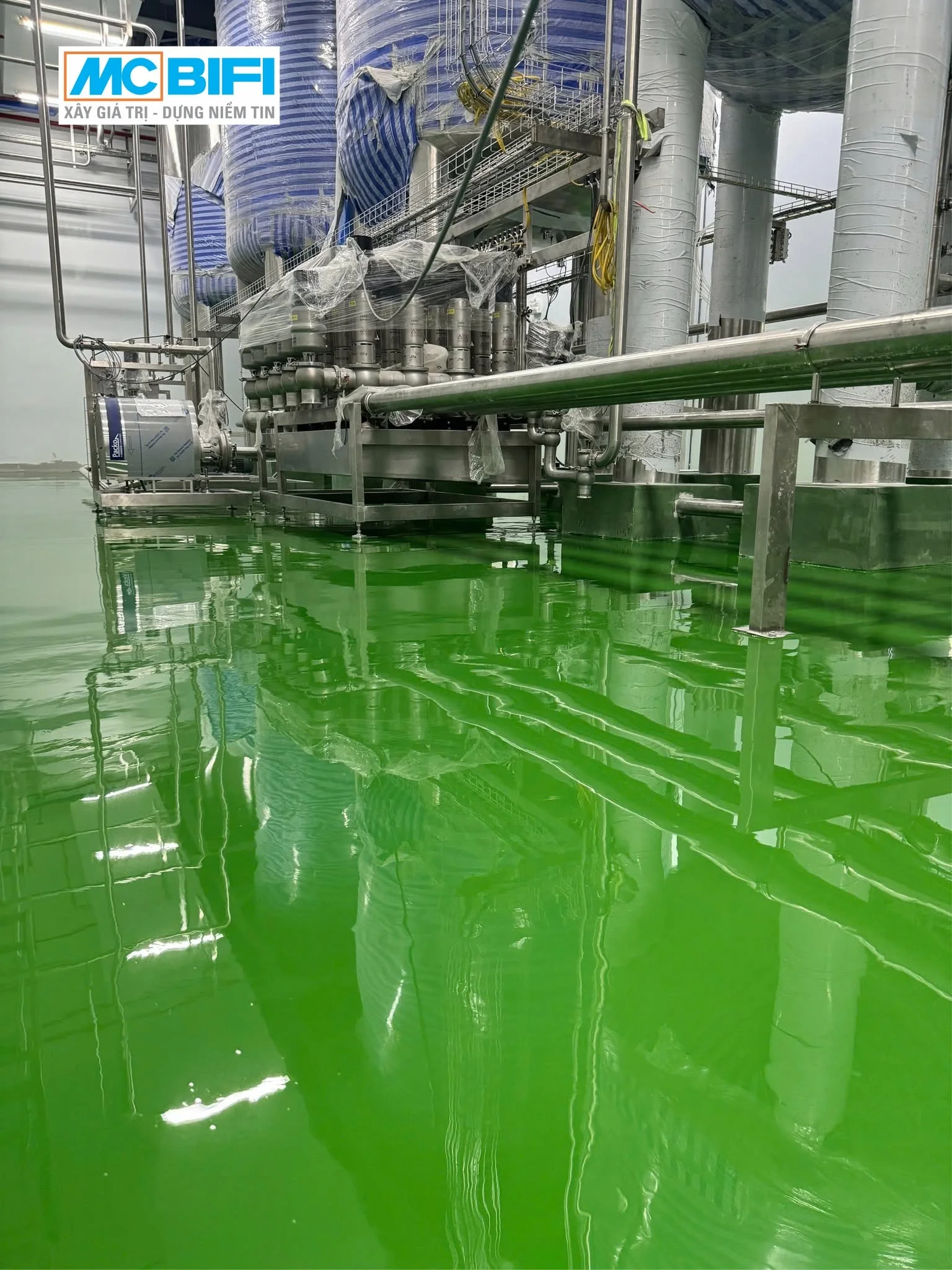 Sàn Epoxy MC Floor màu xanh lá cây bóng loáng trong nhà xưởng công nghiệp với hệ thống máy móc