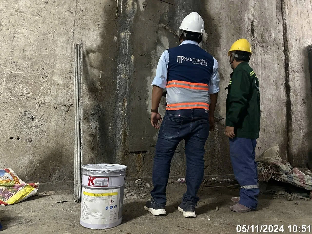 Hai kỹ sư xem xét thùng hóa chất xử lý thấm vách tầng hầm