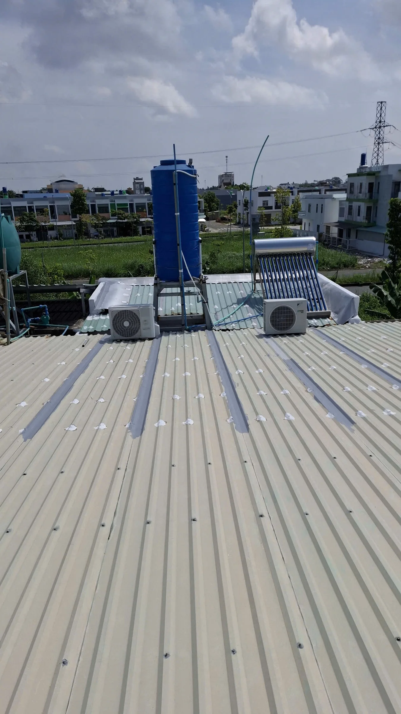 Chống dột mái tôn tại Hồ Chí Minh với máy lạnh, bình nước nóng năng lượng mặt trời và bồn nước.