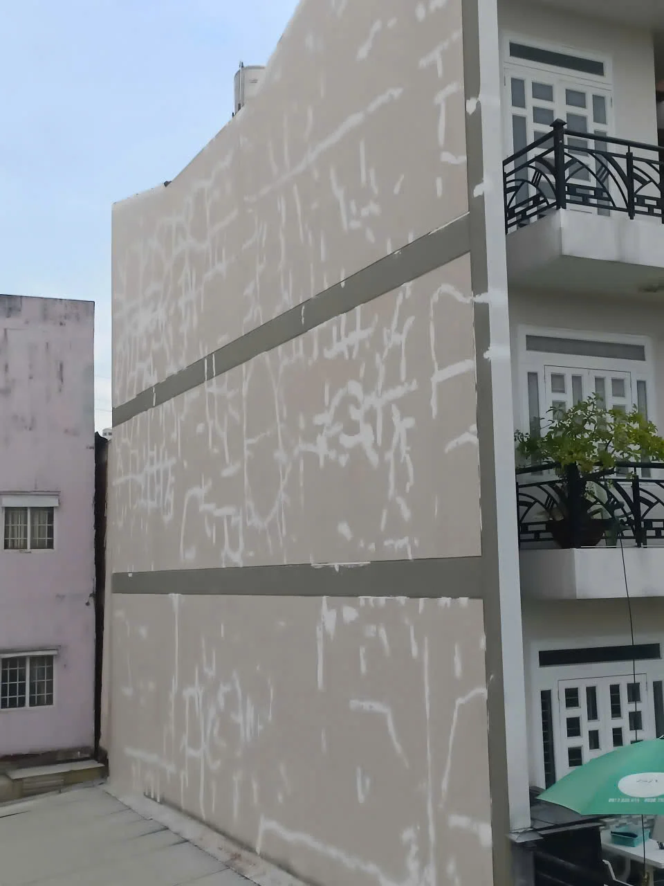 Tường ngoại thất đang được trám vết nứt, sửa chữa, với ban công và cửa sổ